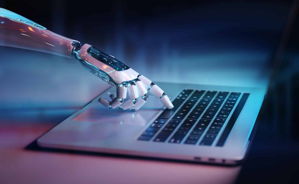 Close-up of a robotic hand pressing a key on a laptop.