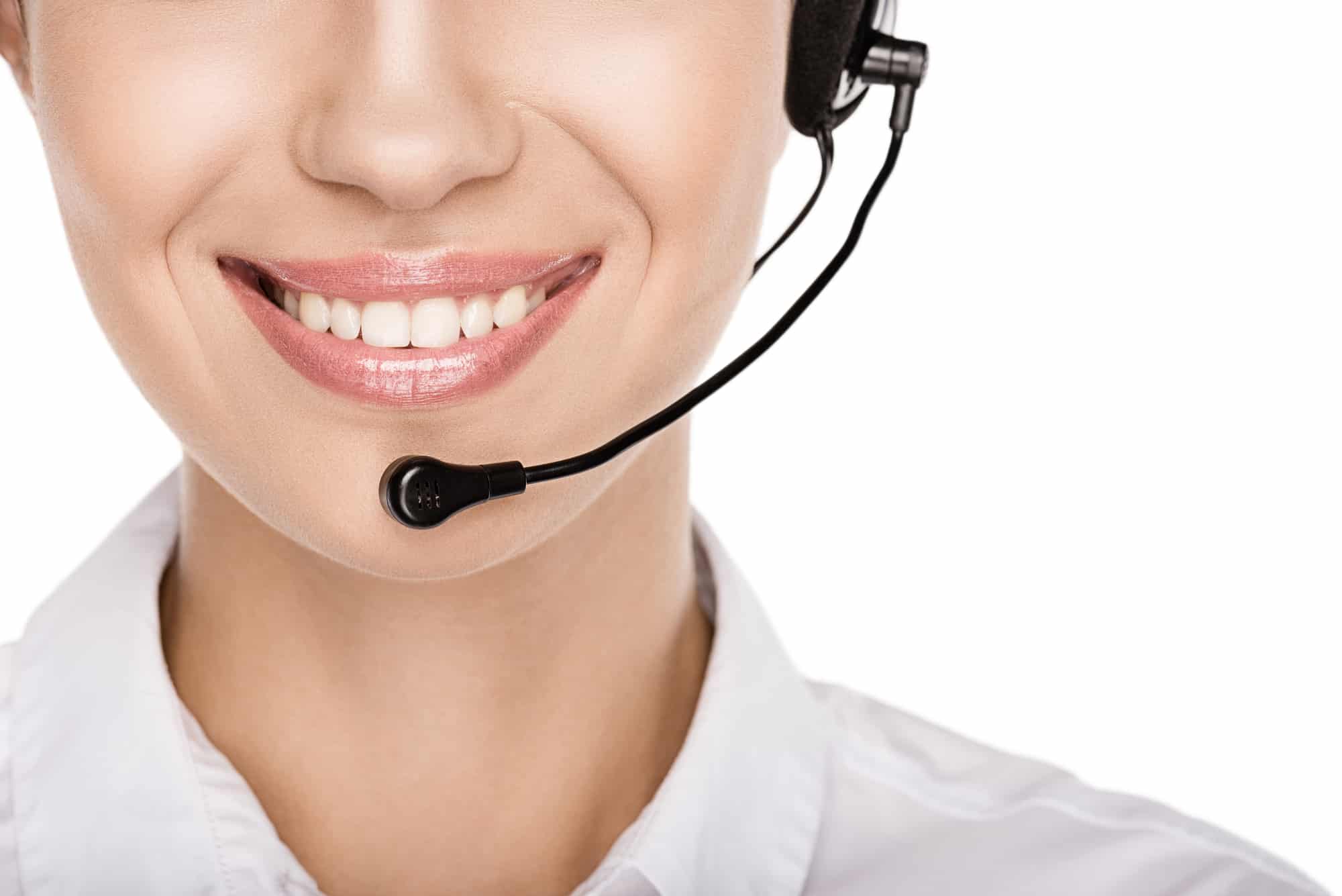 A closeup of a call representative’s smile behind their headset.
