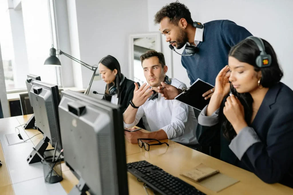 A call center manager shares coaching best practices and examples with an agent sitting in a row of agents.