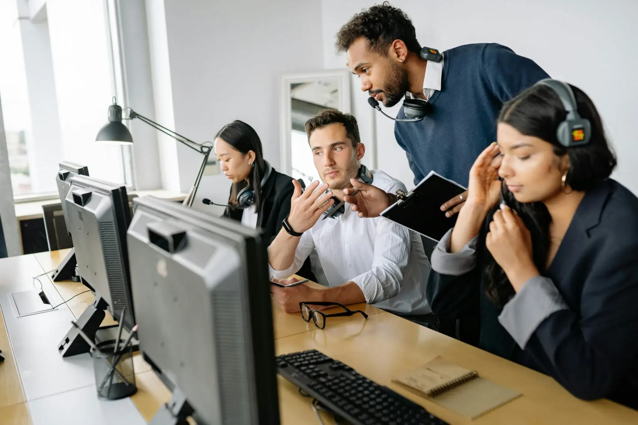 A call center manager shares coaching best practices and examples with an agent sitting in a row of agents.